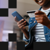 Smiling woman in denim jacket looking at her credit card and smartphone