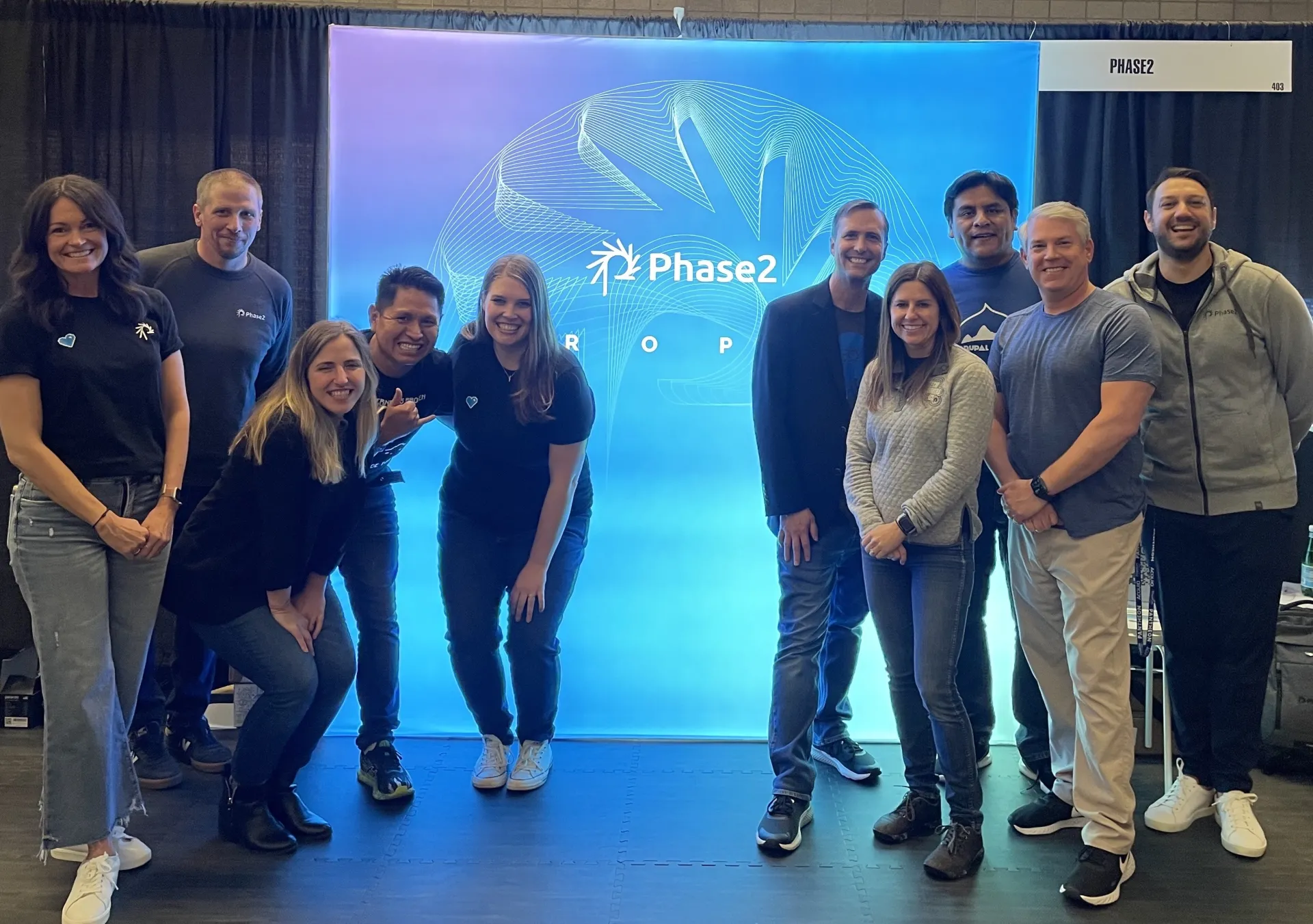 Ten people posing in front of Phase2 sign