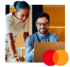 Woman looking over mans shoulder looking at a laptop. Mastercard logo in lower right corner.