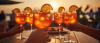 Glasses of orange cocktails with ice and slices, sunset background.